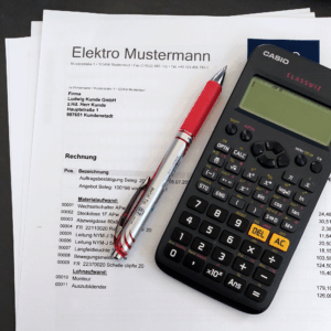 Foto einer Rechnung mit einem Stift und einem Taschenrechner - Wir bearbeiten Ihre laufende Buchhaltung.
